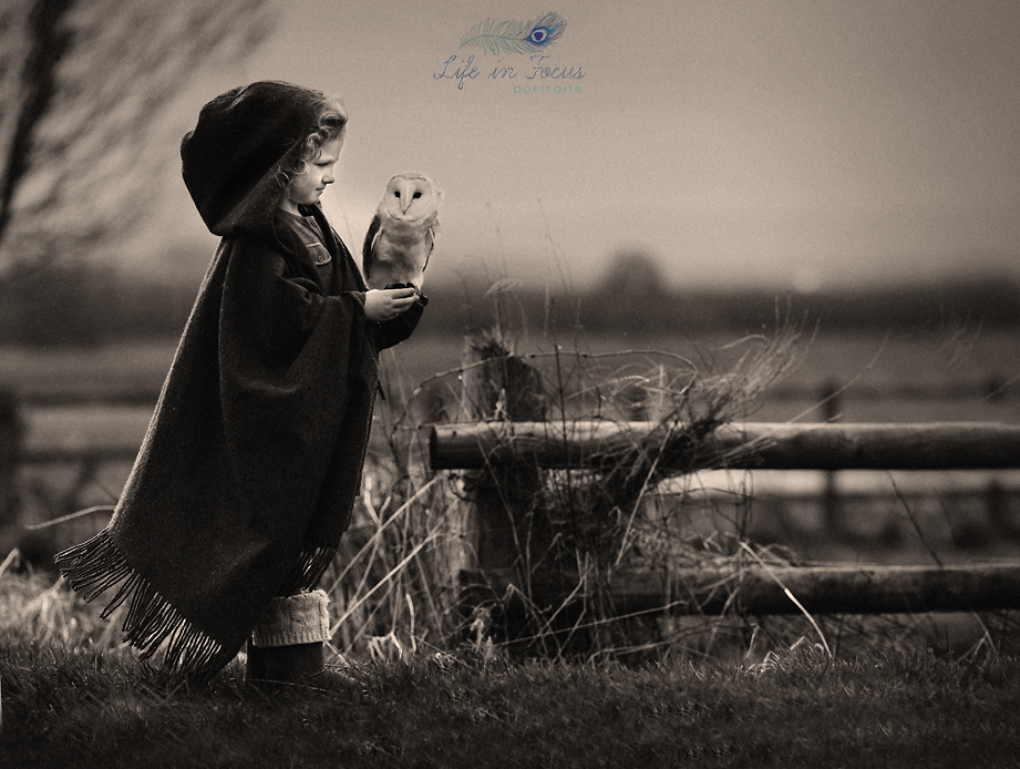 Girl holding owl in field