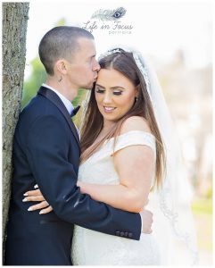 Bride and groom embrace under tree spring wedding Levenside Park Dumbarton Life in Focus Portraits wedding photographer Cardross Dumbarton