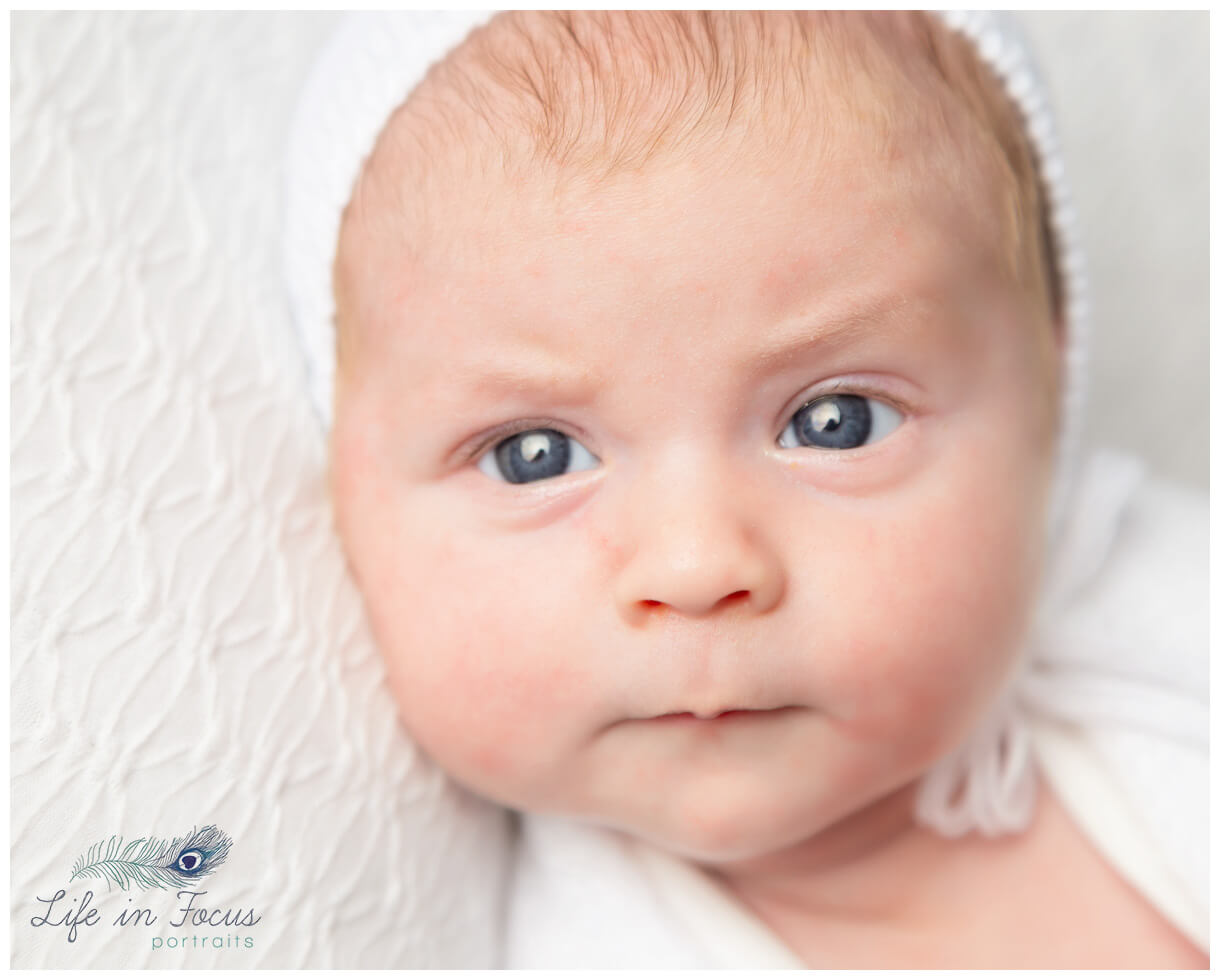 close up portrait photo newborn baby with eyes open in white bonnet Life in Focus Portraits newborn baby photoshoots Arrochar Argyll and Bute