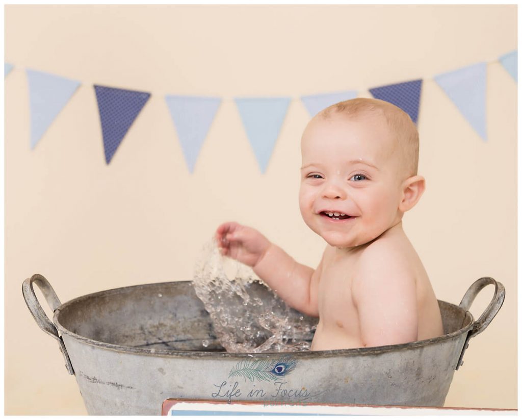 baby splashing in bath tub at first birthday photoshoot Life in Focus