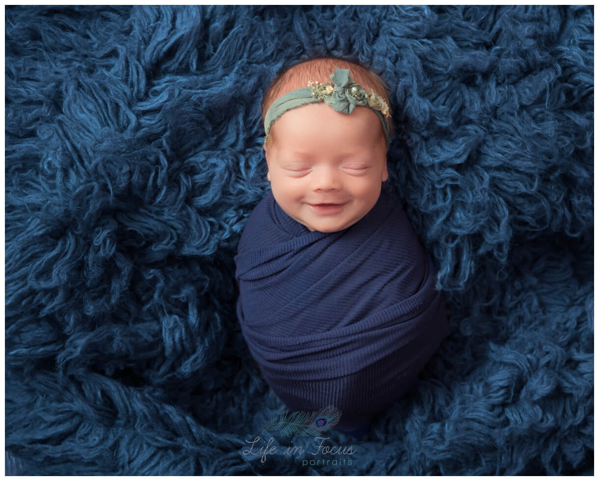 smiling newborn baby girl wrapped with jade headband Life in Focus Portraits newborn baby photography studio Rhu Helensburgh