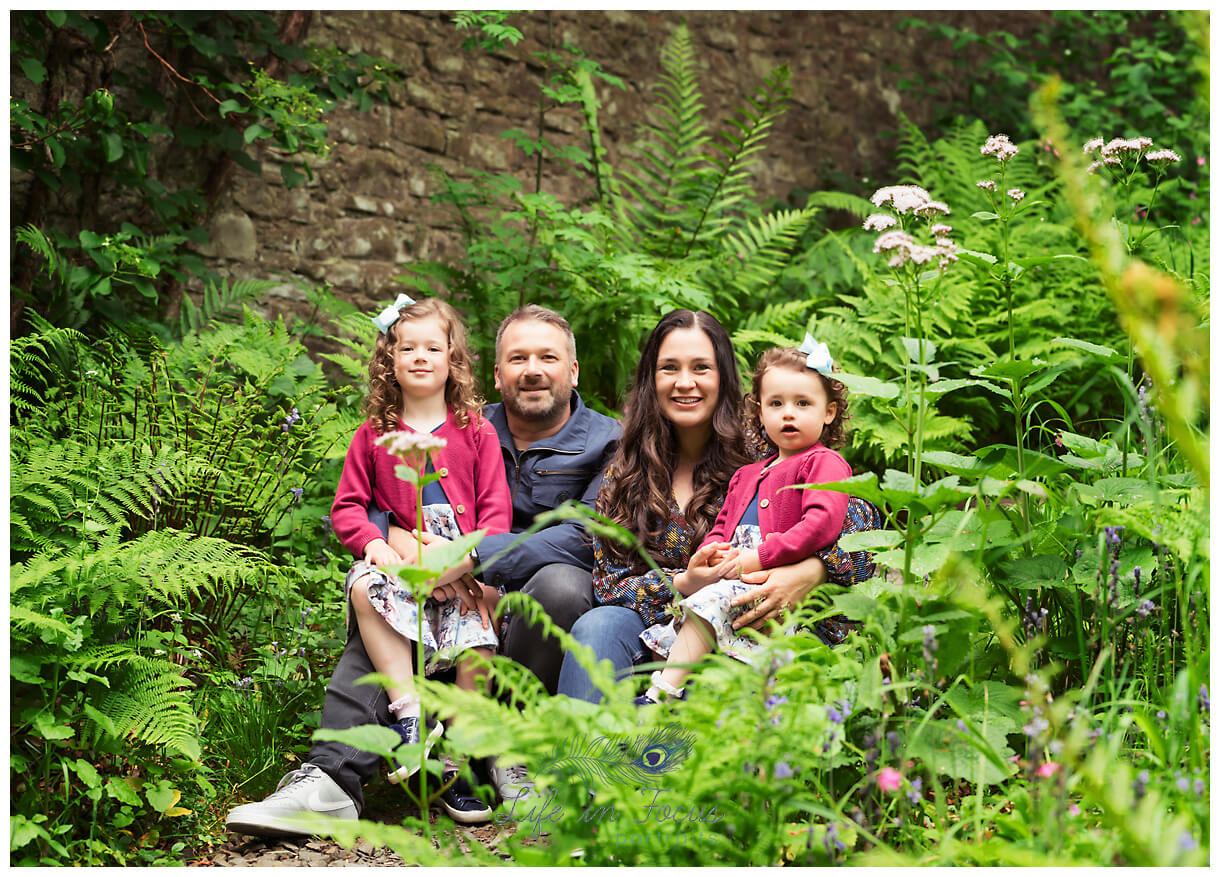photo of family with 2 little girls sitting in ferns outdoor family photos Helensburgh